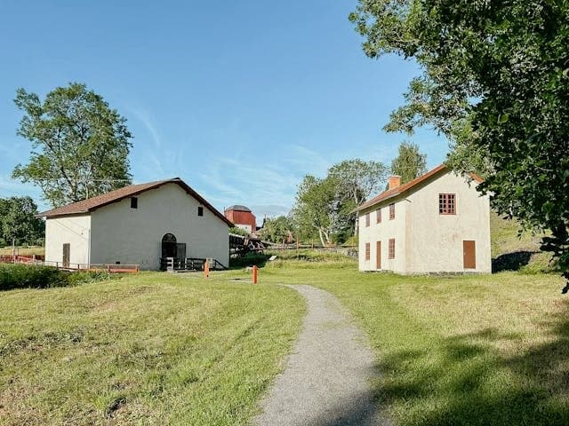 Charmiga vita byggnader med tegeltaken ligger omgärdade av grönska och trädgård. En idyllisk väg löper mellan husen, perfekt för detta autentiska landsbygdsfastighet.